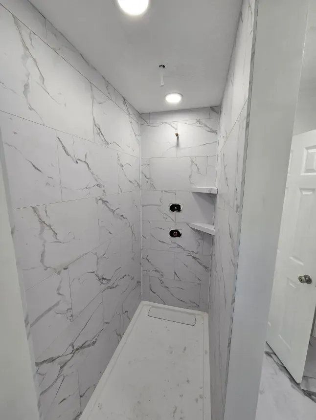 A bathroom with marble tiles and a walk in shower.
