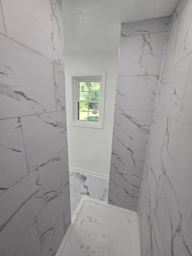 A bathroom with marble tiles and a window.