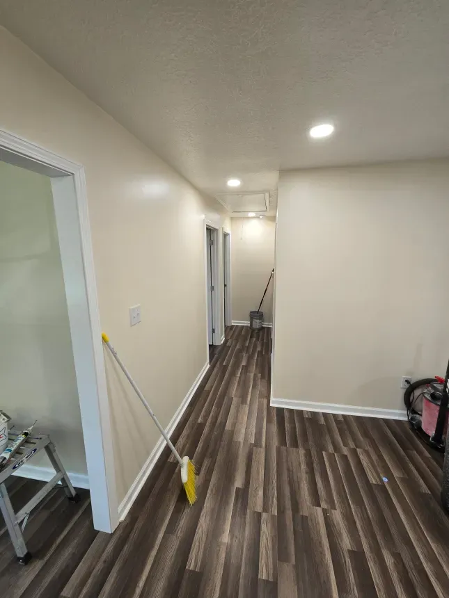 A long hallway with hardwood floors and white walls.