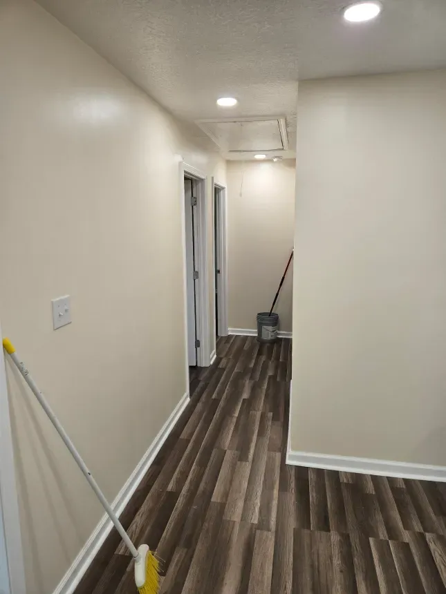 A hallway with hardwood floors and a mop in it.