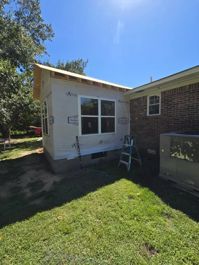 A ladder is sitting in front of a house that is being remodeled.