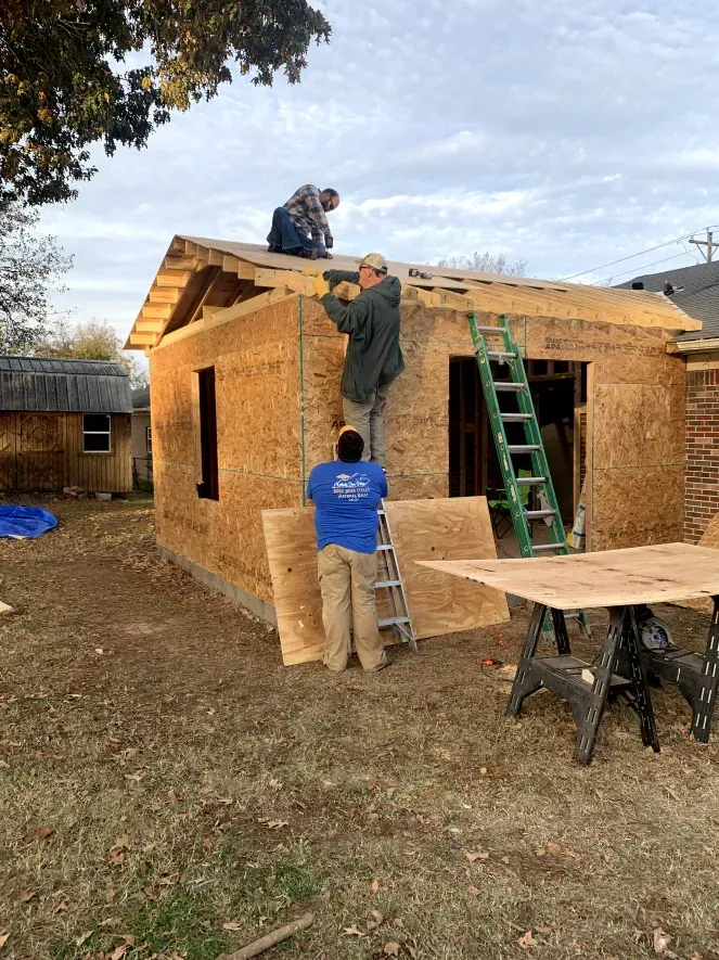 A group of men are working on the roof of a house.