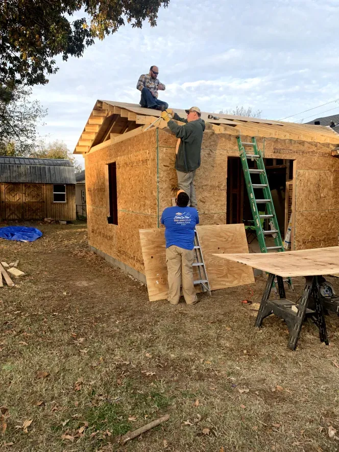 Two men are working on the roof of a house.