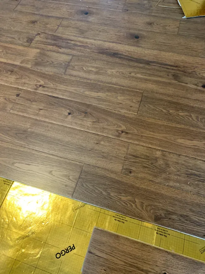 A close up of a wooden floor with a yellow foil underneath it.