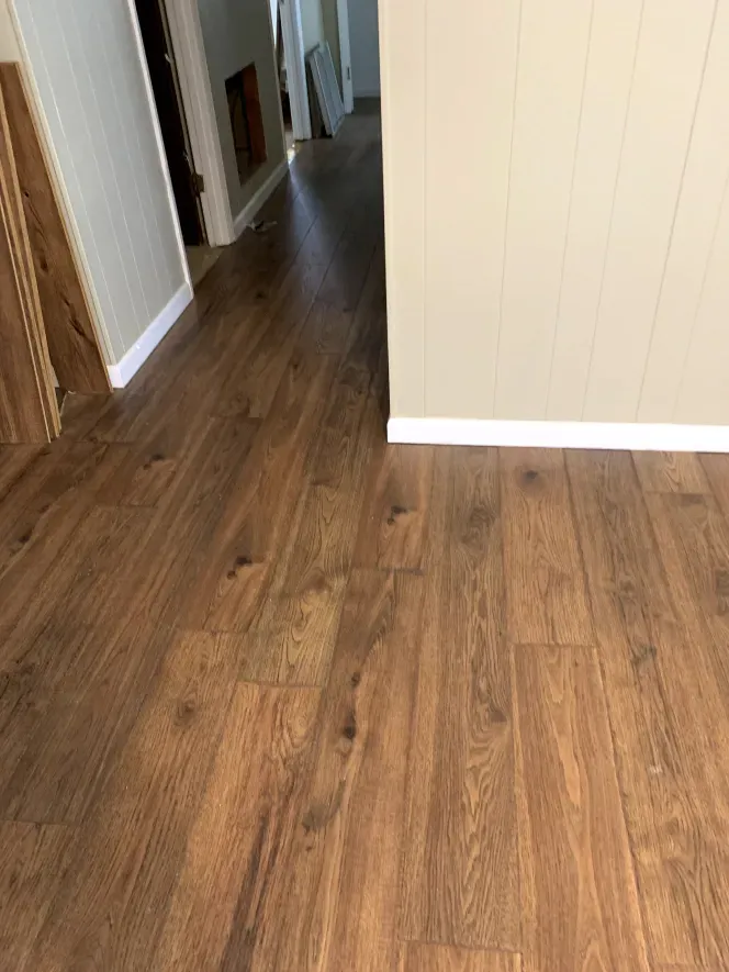 A hallway with a wooden floor and a white wall.
