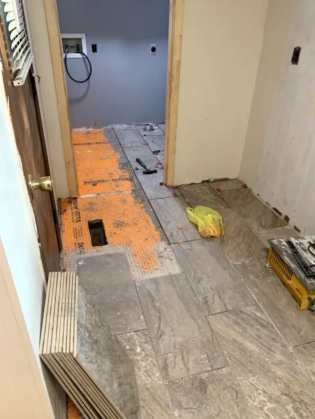 A bathroom is being remodeled and the floor is being tiled.
