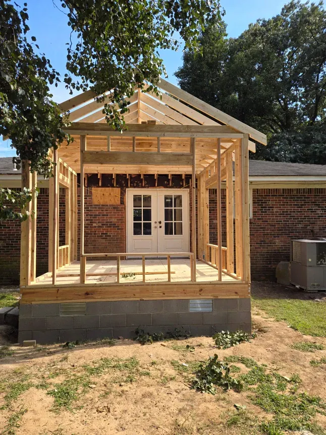 A wooden structure is being built on top of a brick house.