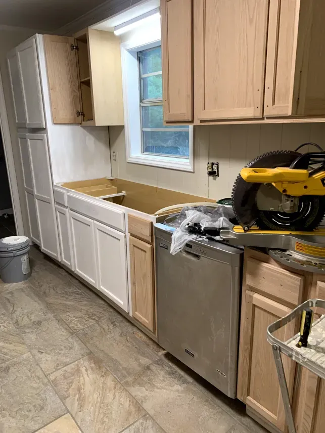 A kitchen is being remodeled with wooden cabinets and a circular saw.