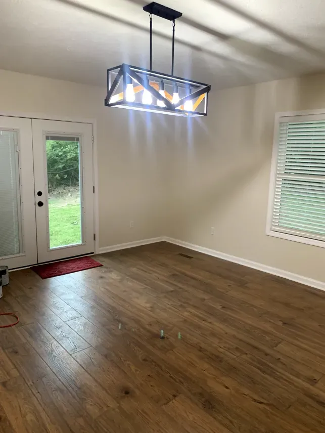 A living room with hardwood floors and a chandelier hanging from the ceiling.