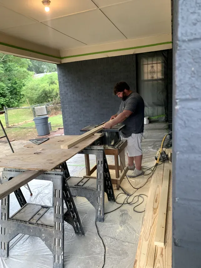 A man is using a circular saw to cut a piece of wood.