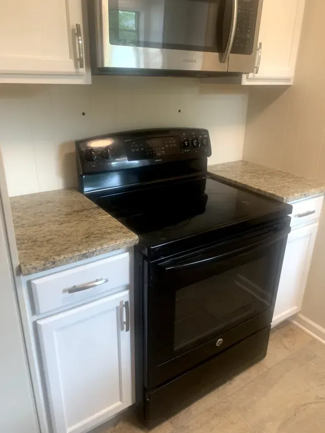 A black stove and microwave are in a kitchen.
