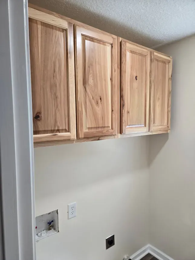 A laundry room with wooden cabinets above the washer and dryer.