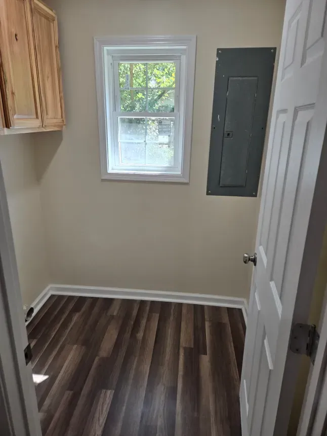 A laundry room with hardwood floors and a window.