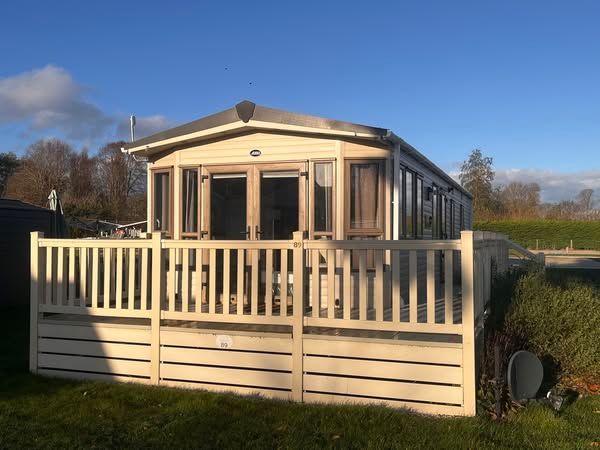 A mobile home with a large deck and fence in front of it.