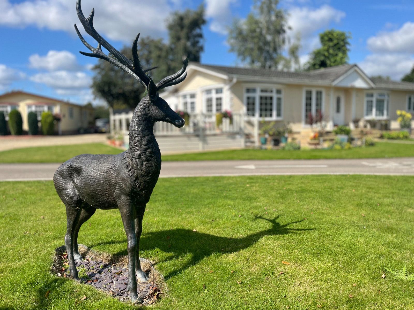 A statue of a deer is standing in the grass in front of a park holiday home