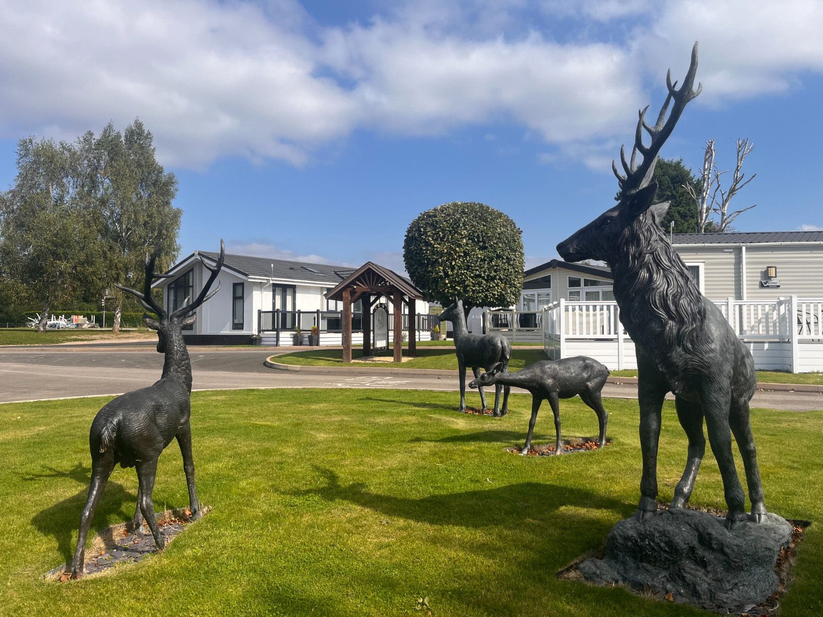 A group of statues of deer standing on top of a lush green field.