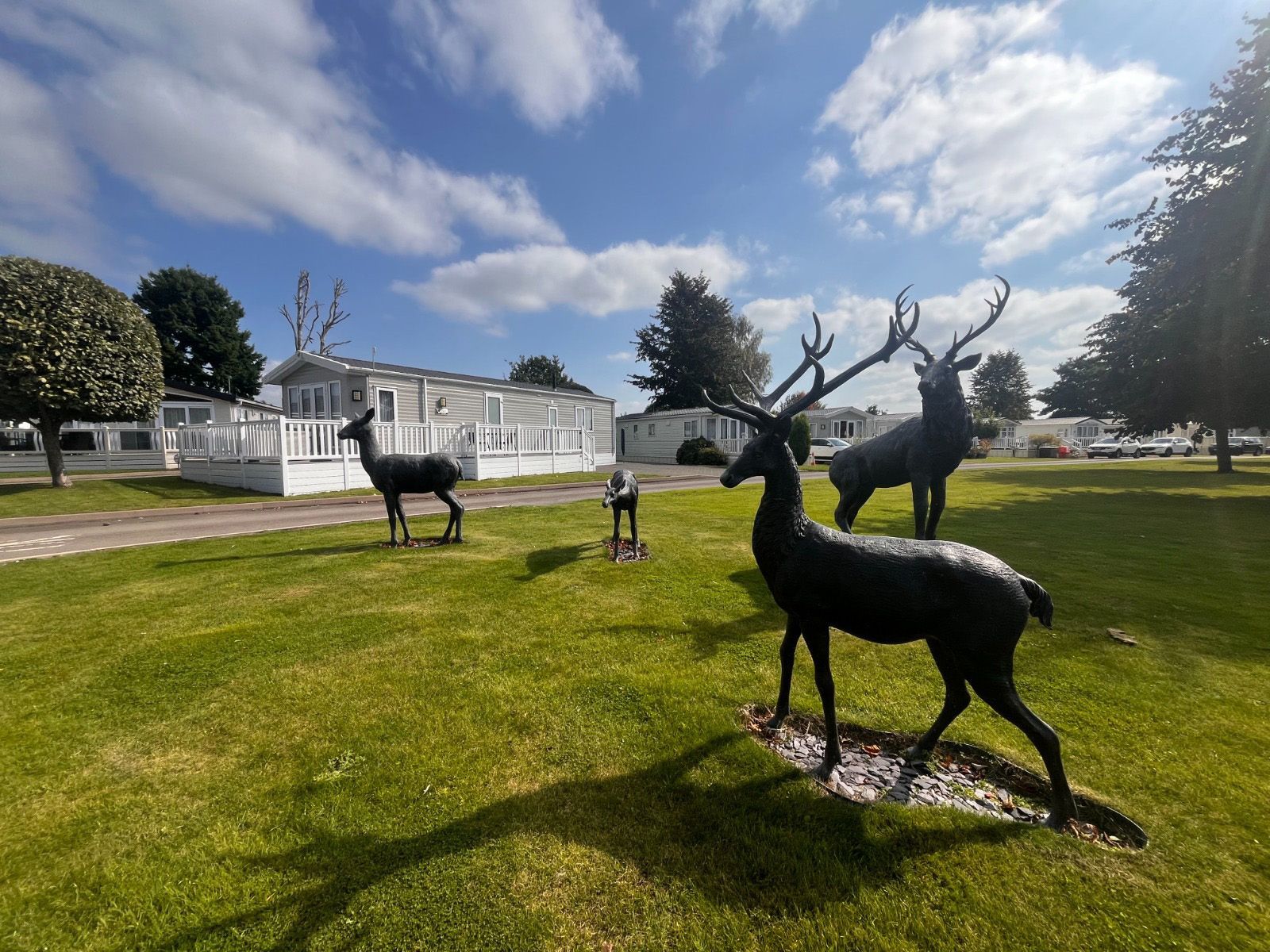 A group of deer statues are standing in a grassy field.