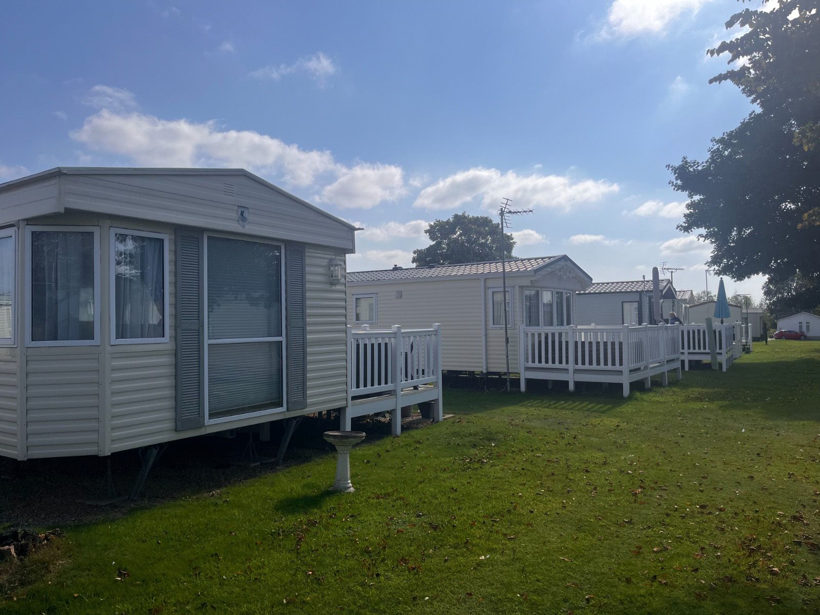 A row of mobile homes are parked in a grassy field.