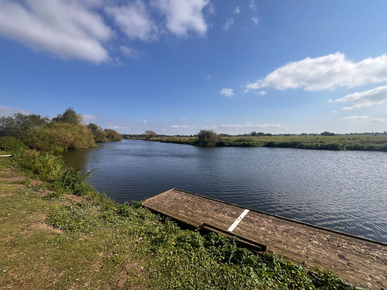 A large body of water with a wooden dock in the foreground.