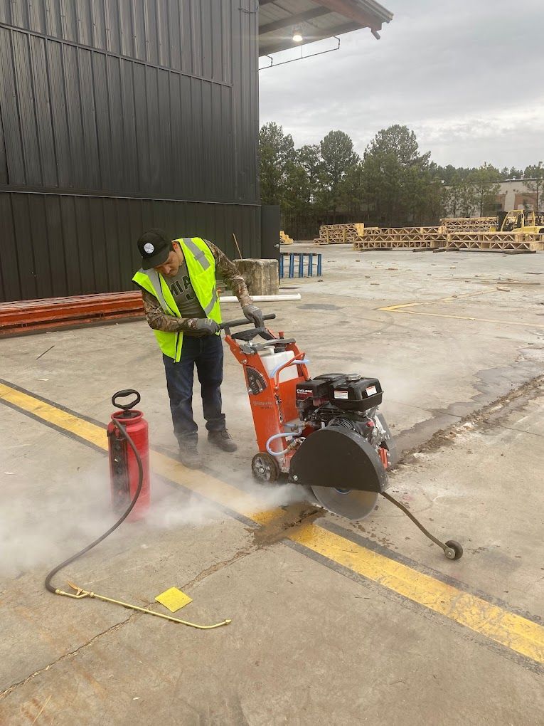 A man is using a concrete saw to cut a hole in the ground.