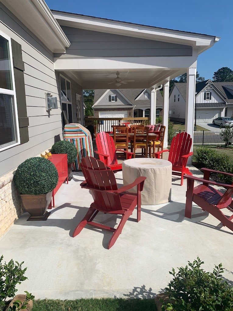 A patio with red chairs and a table under a covered porch.