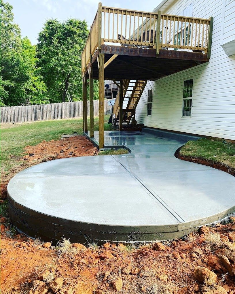 A concrete patio with a wooden deck underneath it.