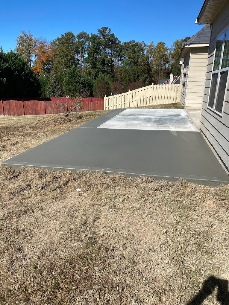 A concrete patio is being built in the backyard of a house.