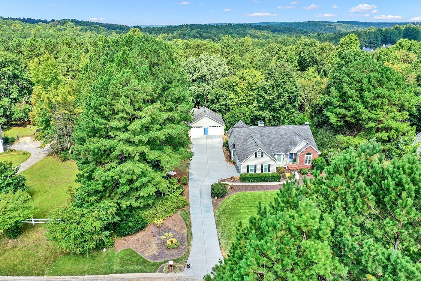 An aerial view of a house surrounded by trees and a driveway.