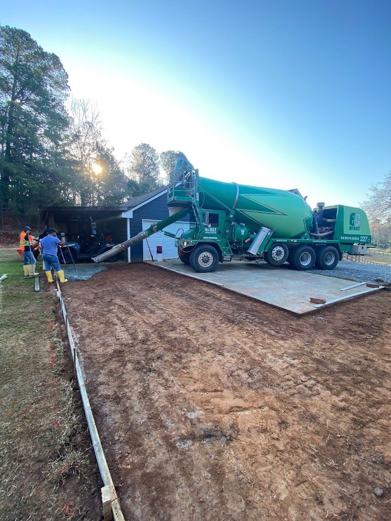 A green concrete mixer truck is pouring concrete into a driveway.