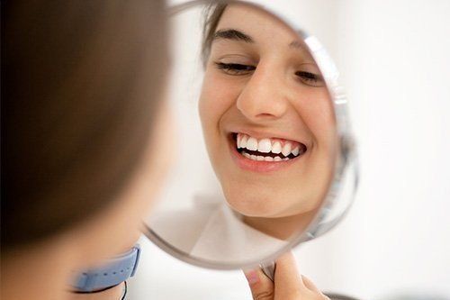 a woman is looking at her teeth in a mirror .