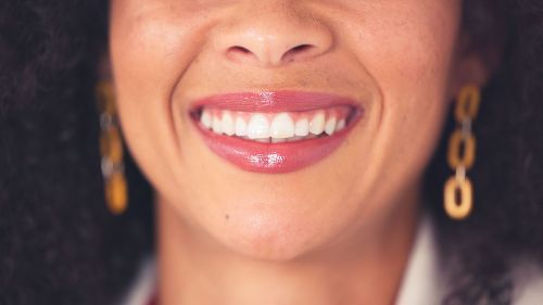 A close up of a woman 's smile with earrings.