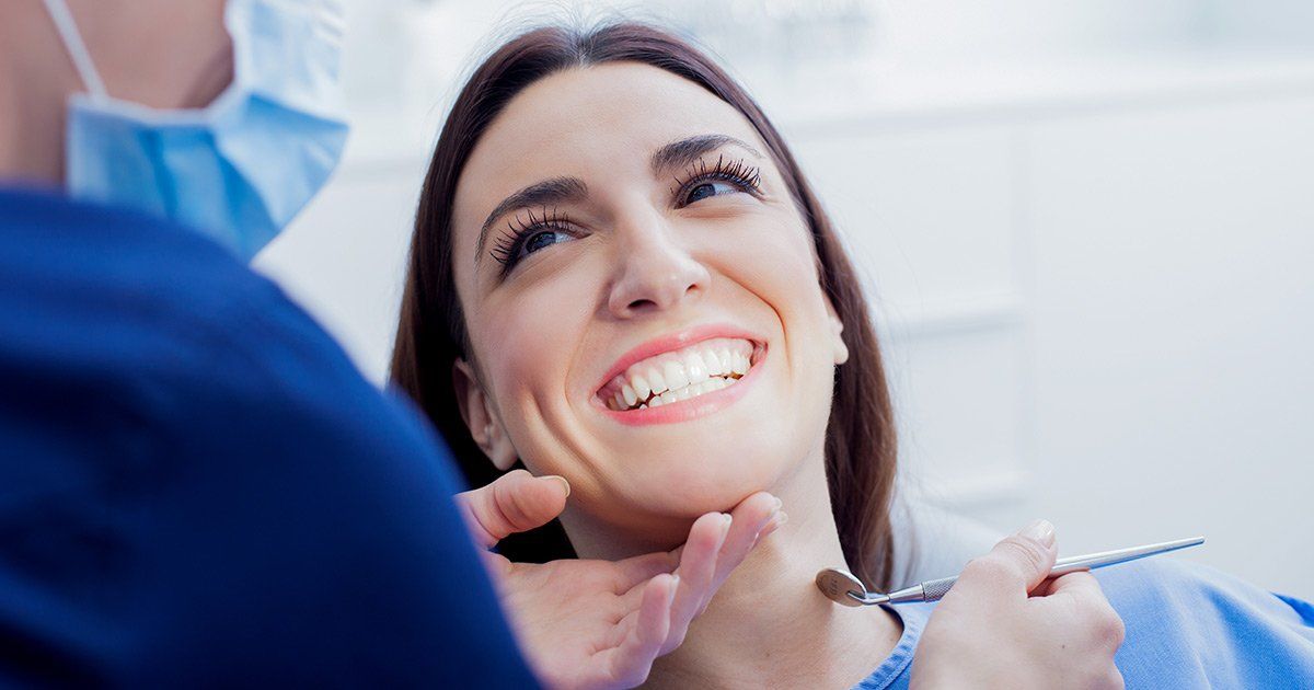a woman is smiling while having her teeth examined by a dentist .
