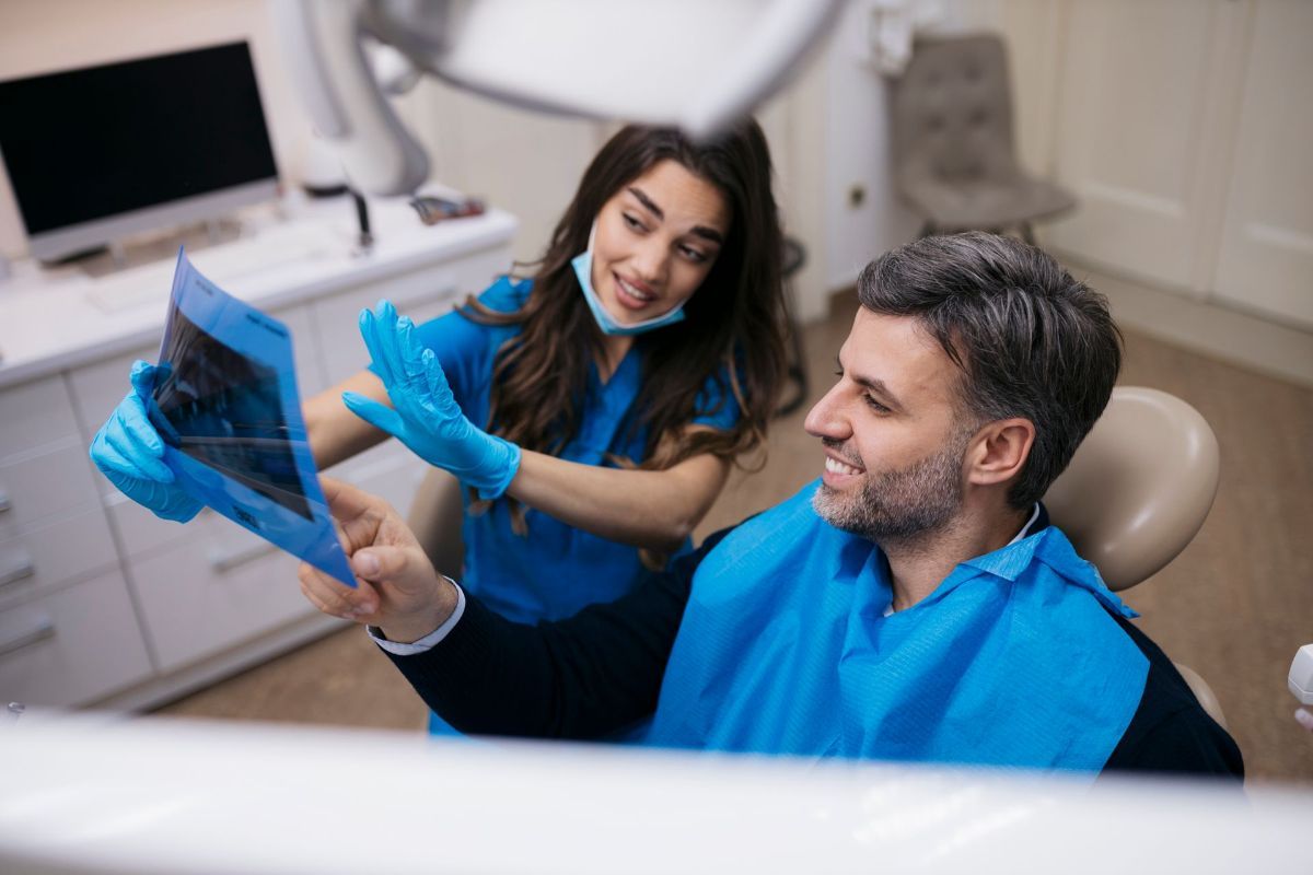 A dentist is looking at an x-ray of a patient 's teeth.