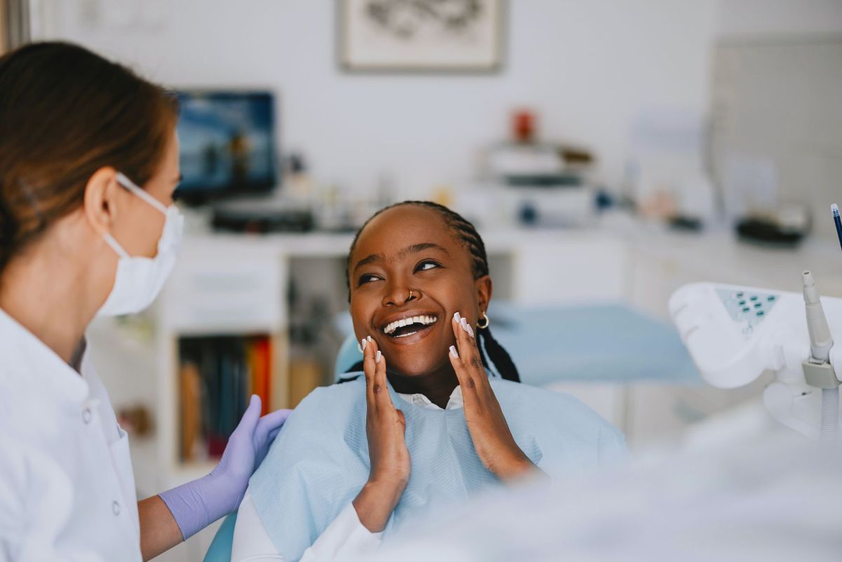 A woman is smiling while sitting in a dental chair.