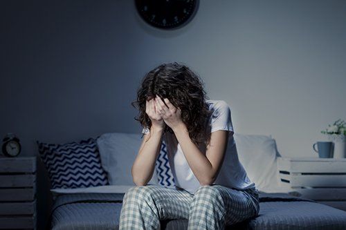 a woman is sitting on a bed with her head in her hands .