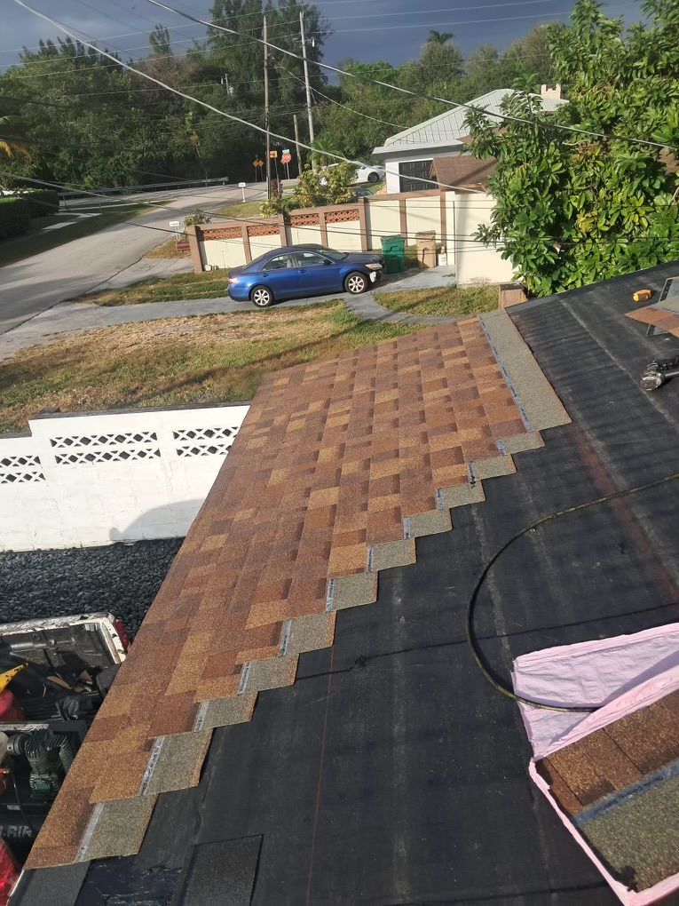 Roof in progress, new shingles laid over black underlayment, brown and tan colors.
