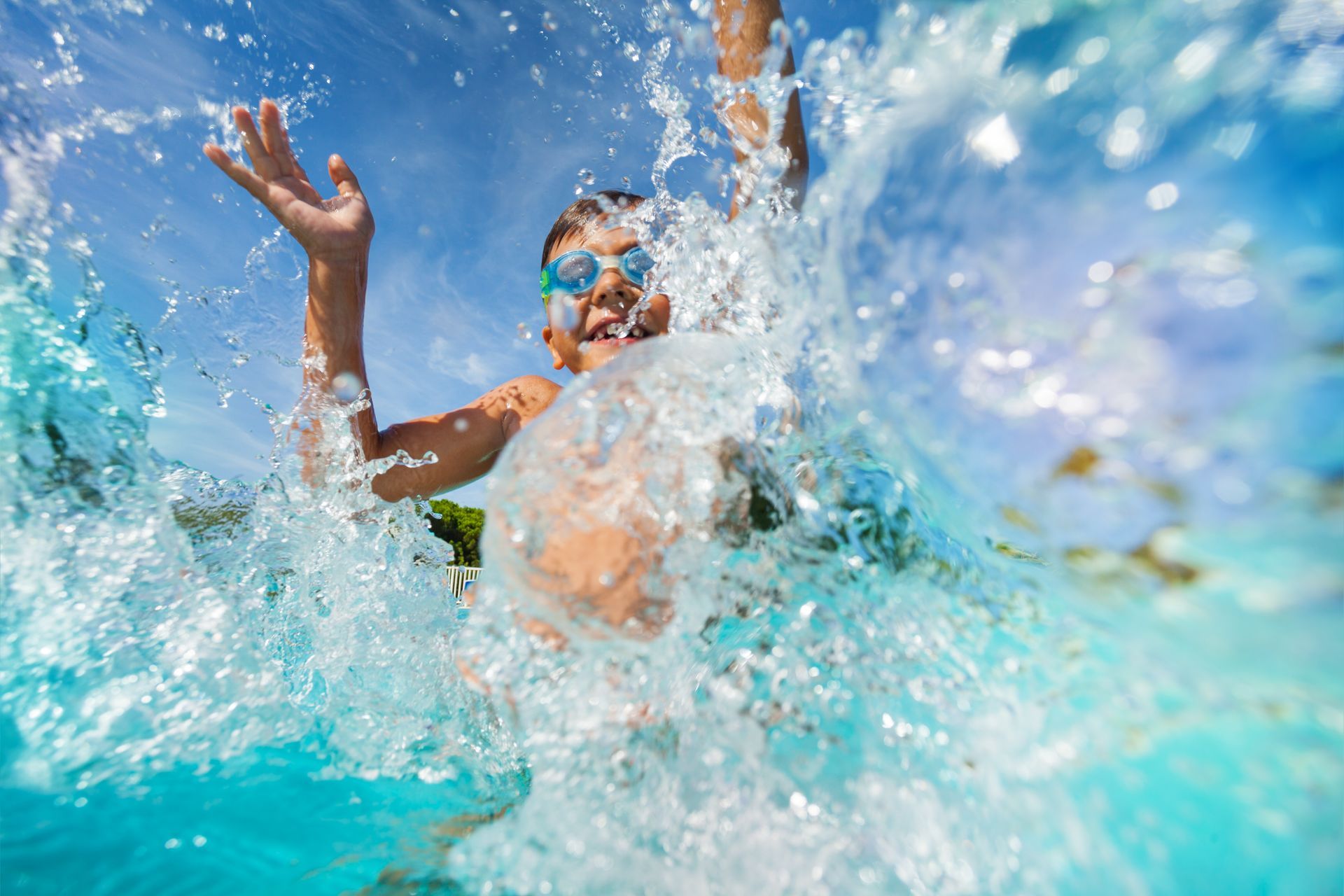 A boy happily splashes water in a pool under the sun. A boy happily splashes water in a pool under the sun.