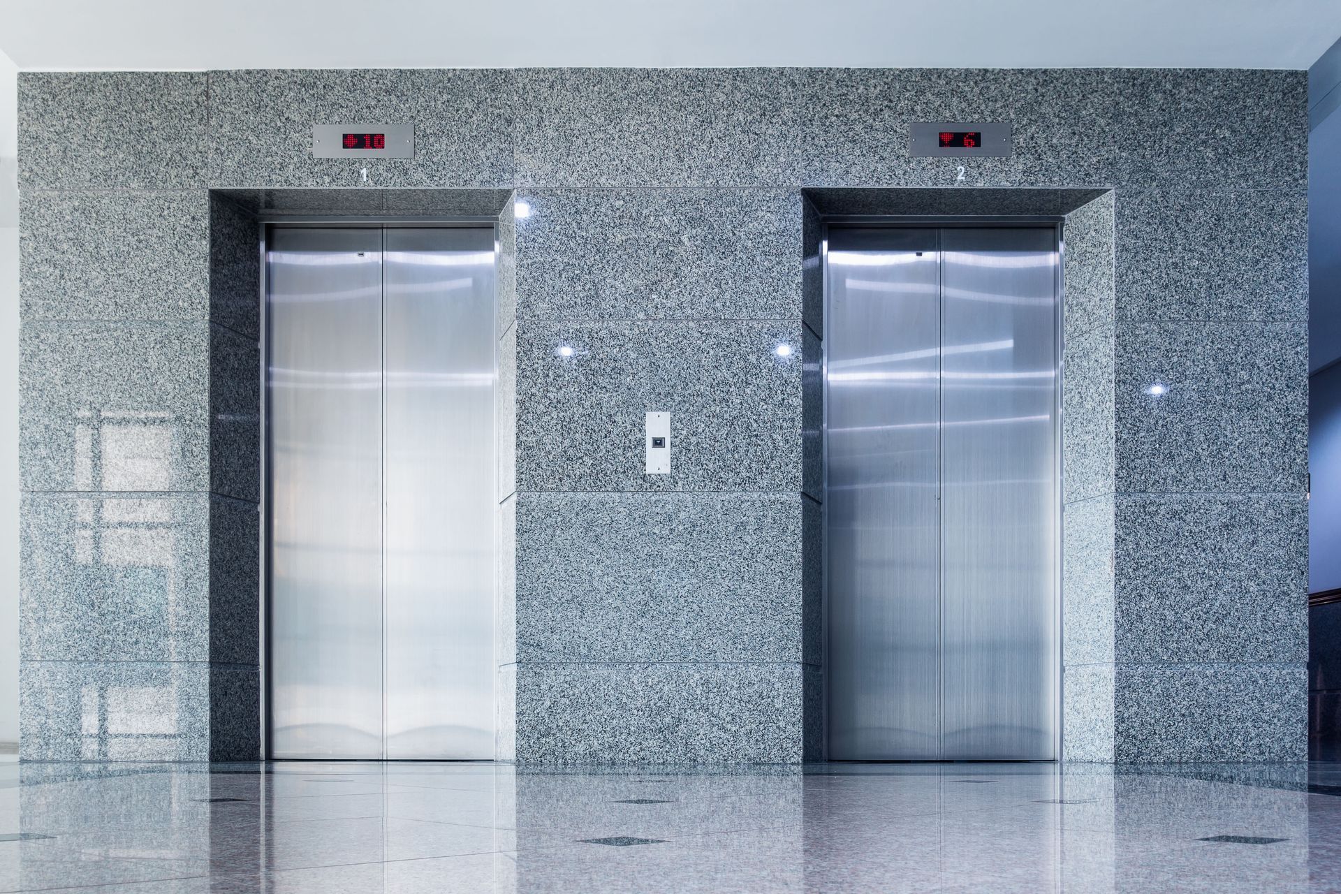 Two stainless steel elevators in a polished stone lobby