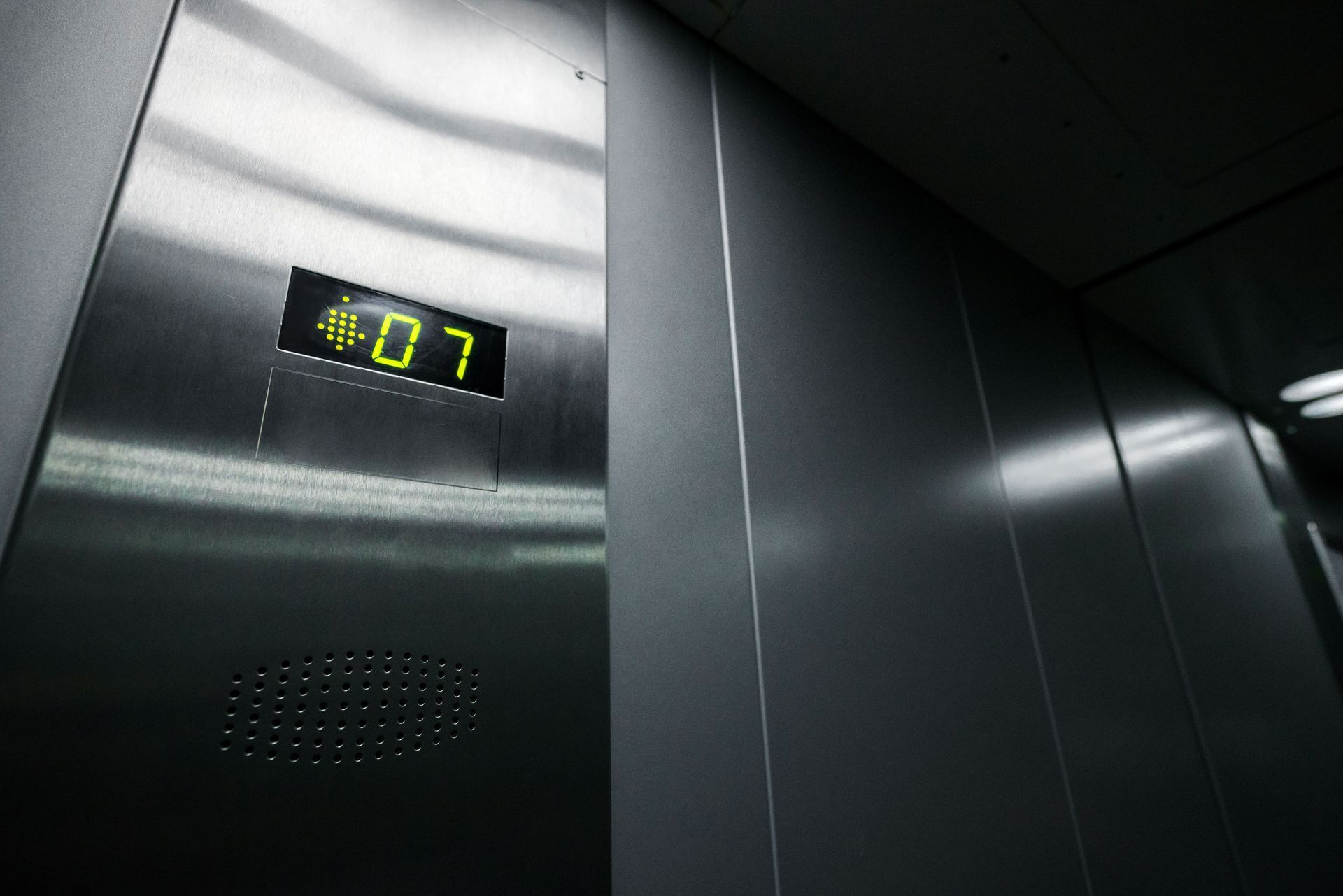 Elevator interior with digital floor display reading 7 and stainless steel walls