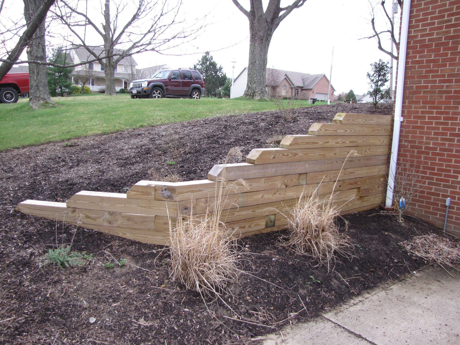 A stone wall surrounds a set of stairs leading up to a house.