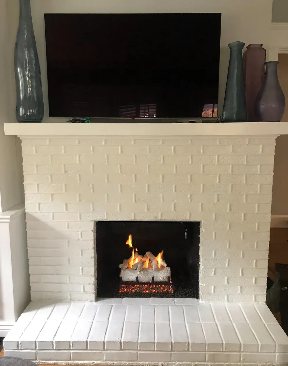 A stone fireplace with a tv mounted above it and a rocking chair in front of it.