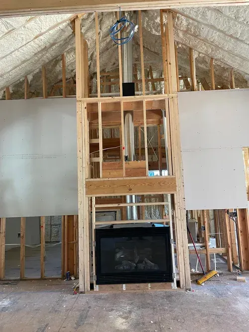 A fireplace is being built into a wall in a house under construction.