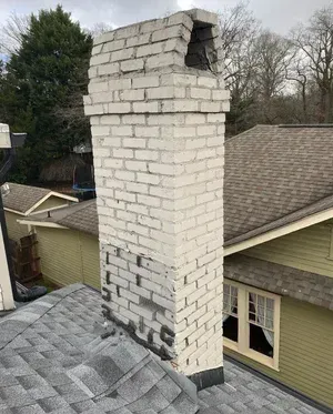 A white brick chimney is sitting on top of a roof.