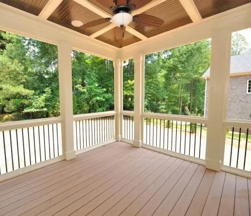 A porch with a ceiling fan and lots of windows.