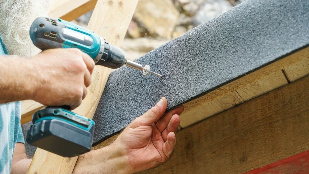 A man is using a drill to drill a hole in a piece of wood.