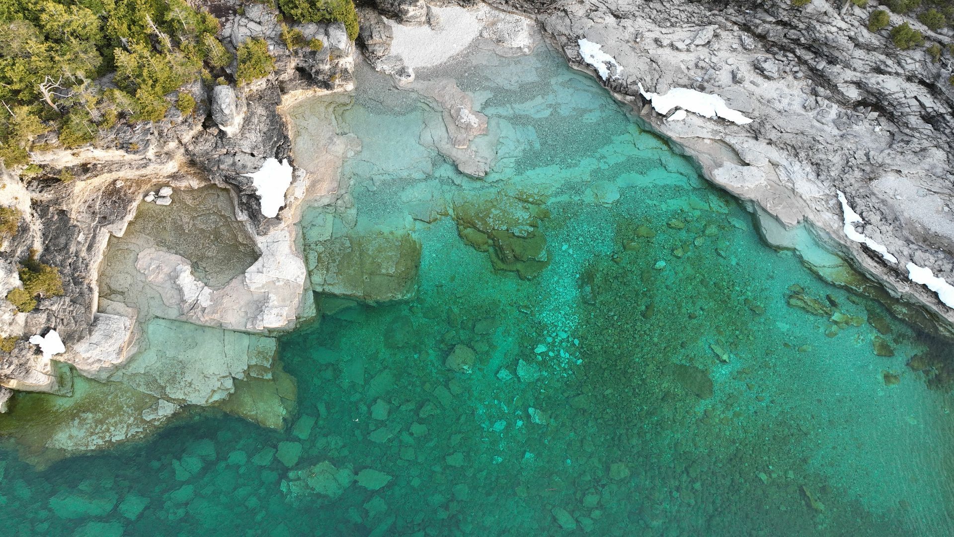 An aerial view of a large body of water surrounded by rocks and trees.