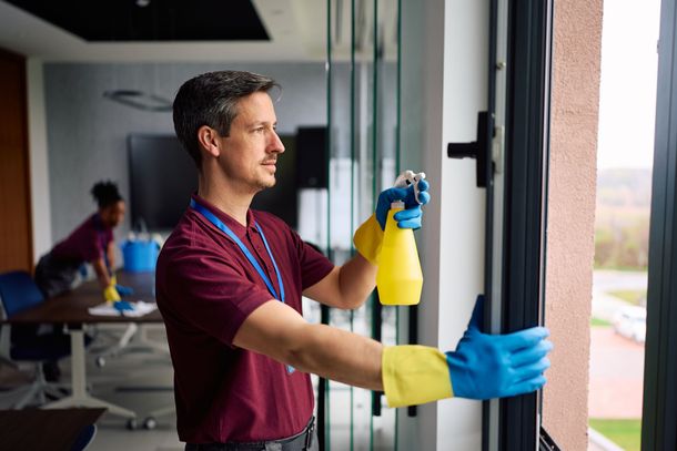 Person mopping a wet floor beside a yellow caution sign in a bright room Person mopping a wet floor beside a yellow caution sign in a bright room