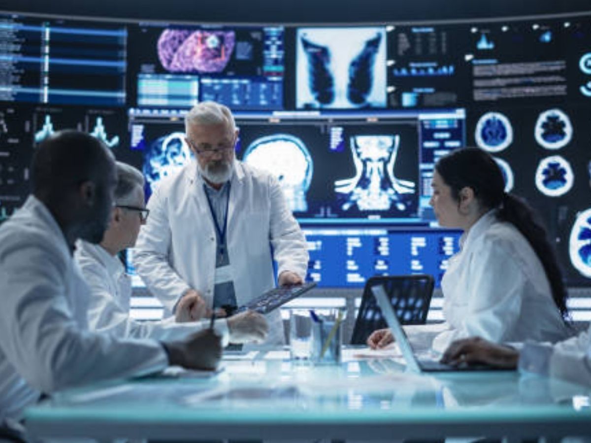 Medical team discussing data and analytics in healthcare, with screens displaying scans.