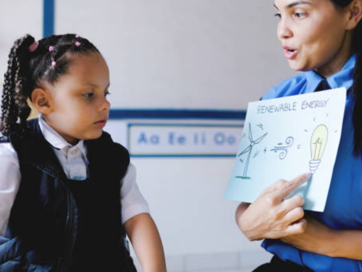 Teacher explaining renewable energy to a young child, highlighting innovations in childcare.