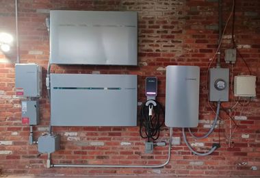 Electrical equipment mounted on a red brick wall, including white control boxes and cable conduits.